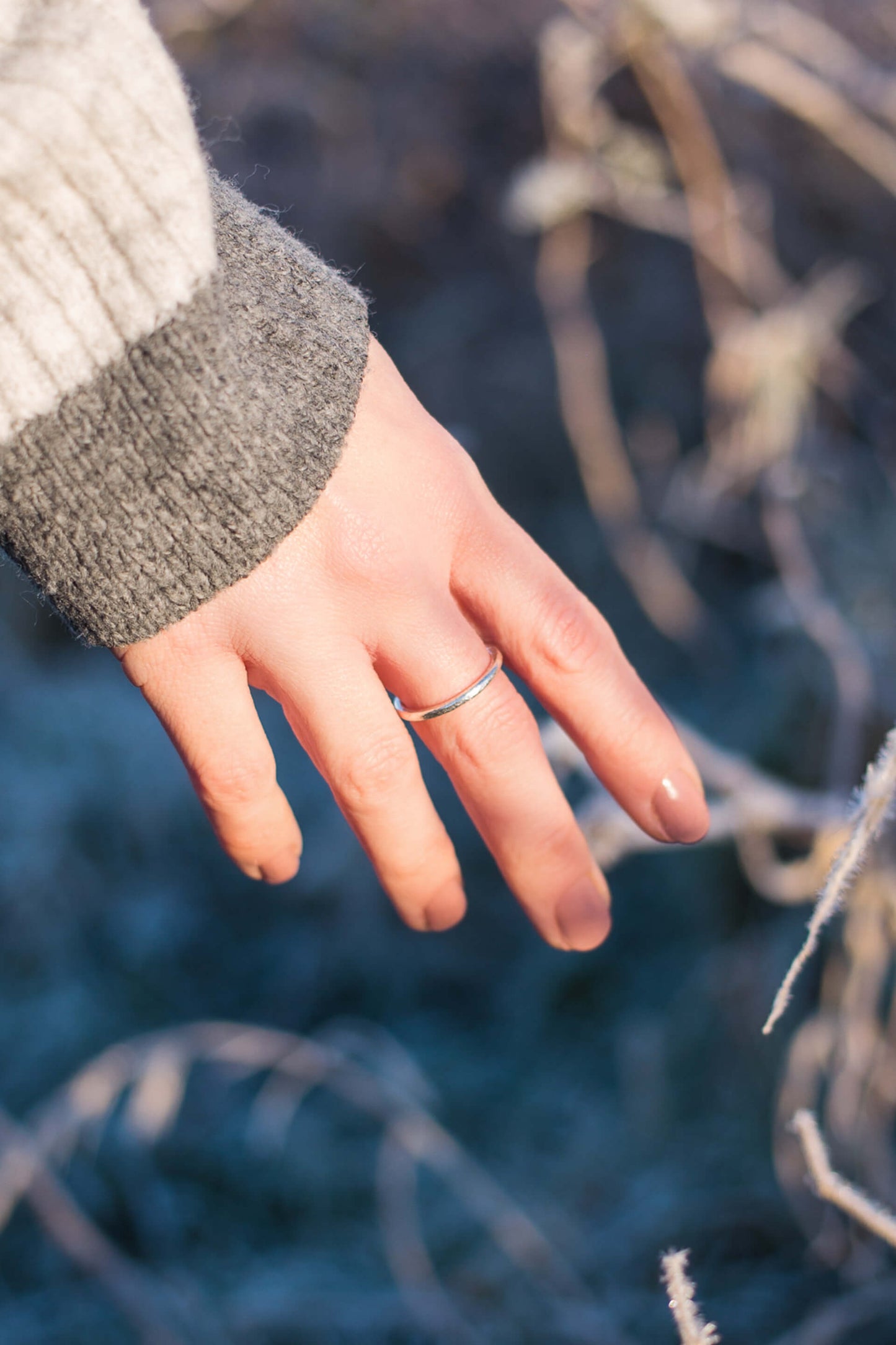 A woman's hand wearing a slim, textured sterling silver ring.