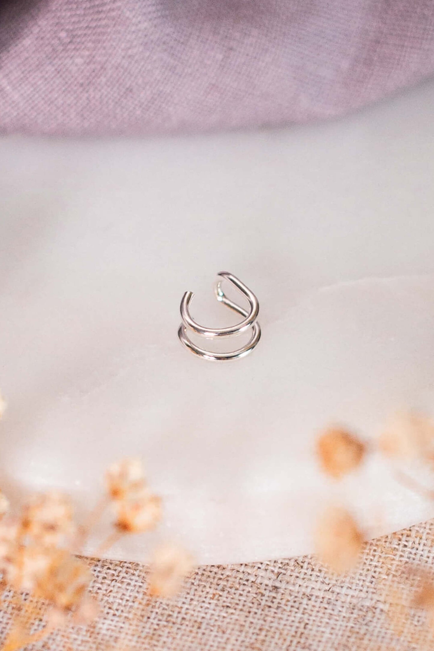 A sterling silver ear cuff on a piece of white marble.