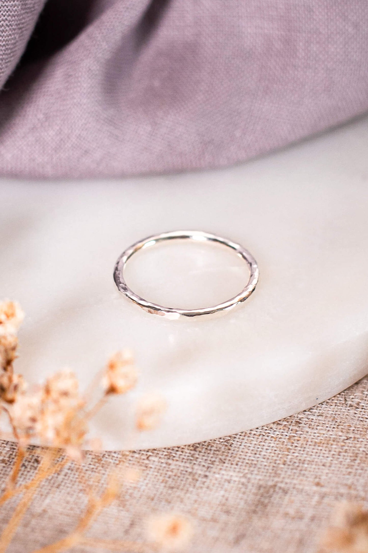 A sterling silver ring band lays on a piece of white marble.