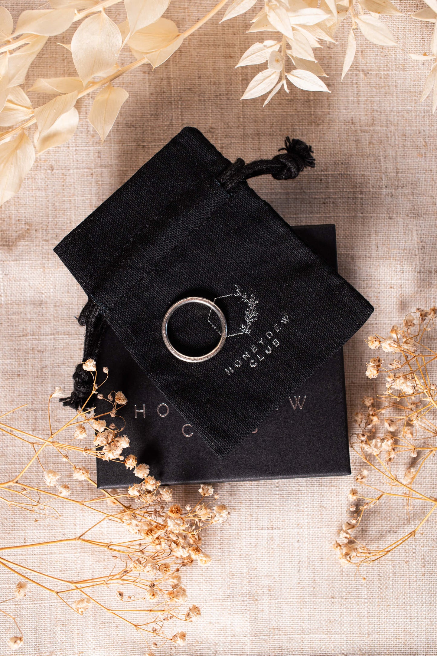 A sterling silver ring band lies on black gift packaging.