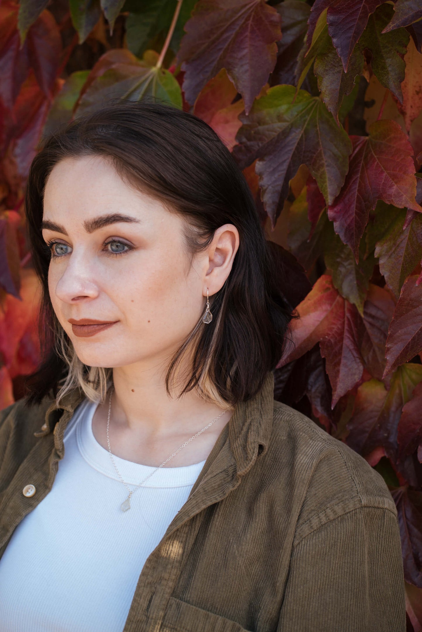 Young woman wearing a casual outfit with a clear gemstone necklace and silver earrings