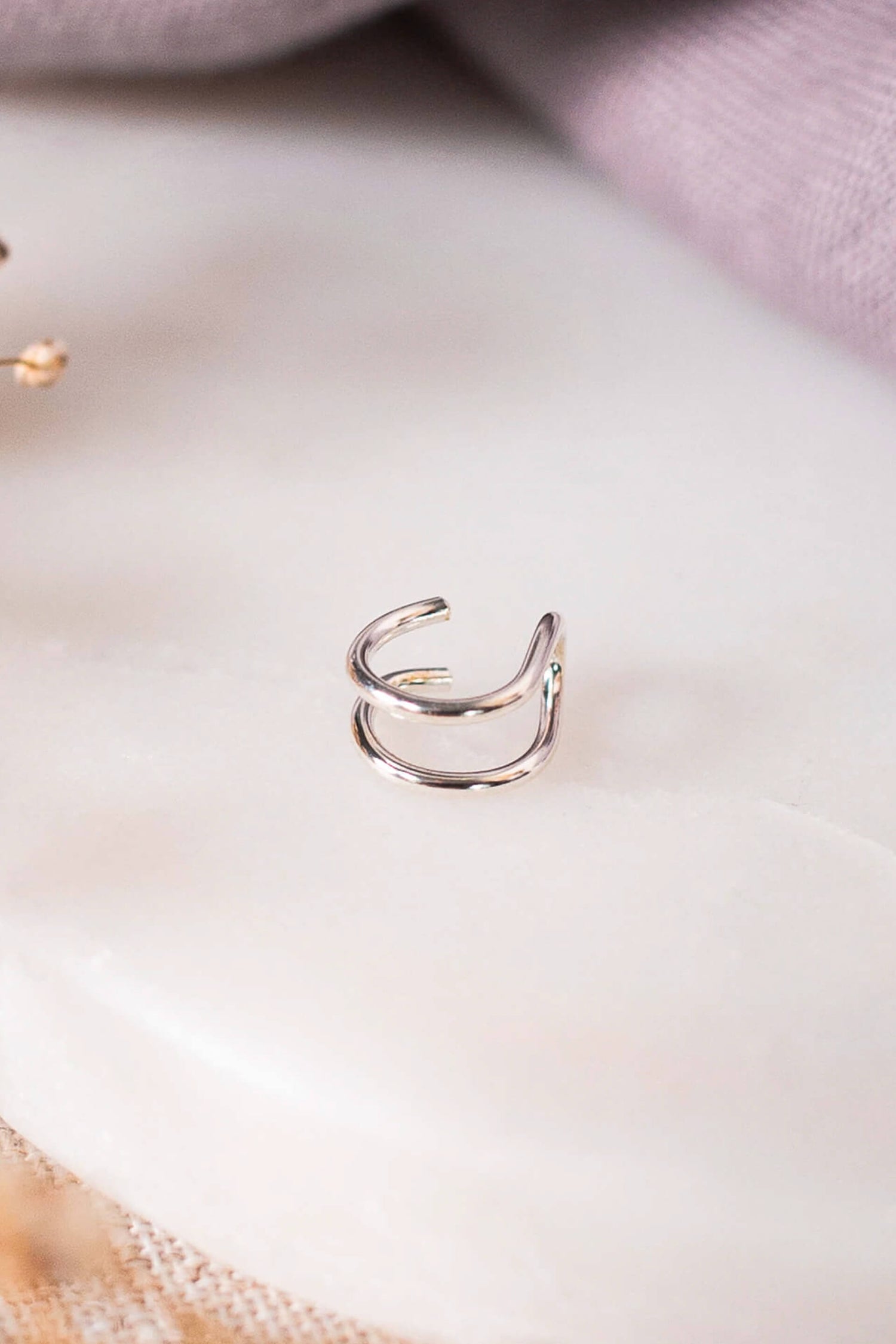 A sterling silver double ear cuff on a piece of white marble.