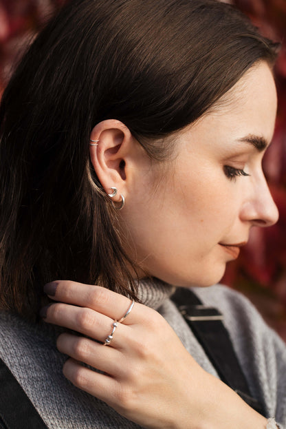 A young woman wearing sterling silver earrings and rings.